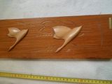 une plaque en bois sur laquelle sont sculptées deux raies