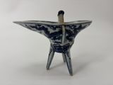 un petit vase bleu et blanc d'où sort un bâton en bois