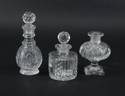 trois bouteilles en verre transparent et un petit vase en verre posés sur une surface noire