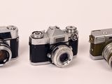 three cameras sitting next to each other on a white surface