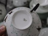 a person holding a tea cup in front of a bunch of plates