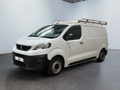 La camionnette blanche est garée dans une grande pièce au sol noir