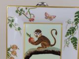 a plate with a picture of a monkey sitting on a tree branch