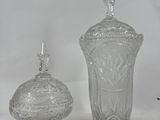 two clear glass vases and a small glass container on a white surface