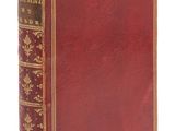 un vieux livre rouge avec des bordures dorées et une couverture aux bordures dorées
