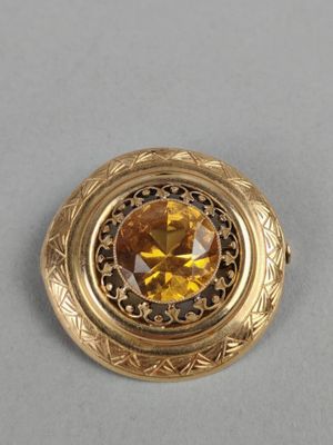 a close up of a gold colored broochle on a gray surface
