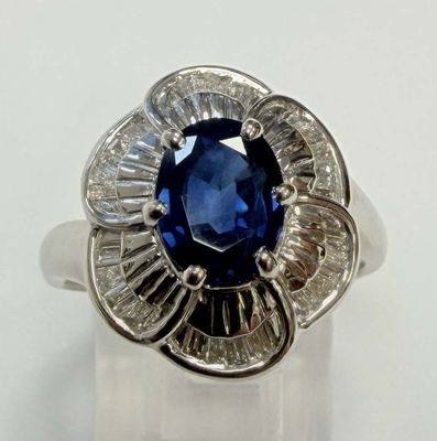 une photo d'une bague en forme de fleur, sertie d'un saphir bleu et de diamants