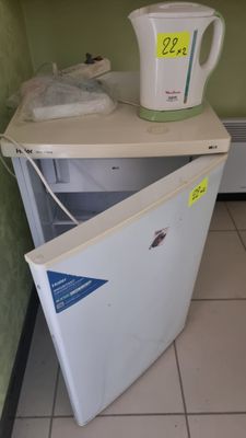 un petit réfrigérateur blanc dans le coin d'une pièce
