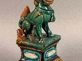 statue d'un lion sur un socle, tenant un panier dans la gueule