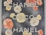 a chanel scarf with flowers on it hanging on a wall