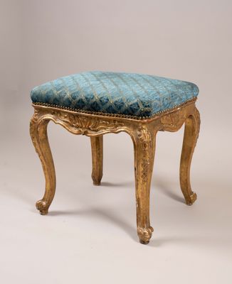 un tabouret ancien dont l'assise est rembourrée de bleu sur fond blanc