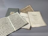 several old music sheets are sitting on a table next to an open book