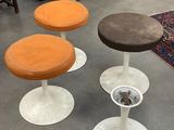 Trois tabourets sont posés dans une pièce où il y a un tapis au sol.