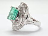 an emerald and diamond ring on a white surface with a white background