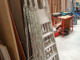 une échelle appuyée contre un mur, à côté d'un tas de bois