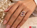woman ' s hand wearing a ring with multicolored stones on it