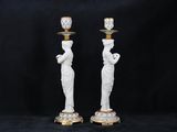 a pair of white and gold candlesticks with statues on them