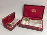 un service d'argenterie dans un coffret rouge et une cuillère en argent dans une boîte rouge
