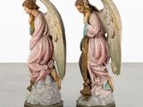 two figurines of angels are sitting on top of a rock