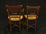 pair of antique chairs with cane seats against a black background