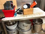 de nombreuses casseroles et poêles posées sur une table dans la cuisine
