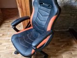 une chaise de bureau noire et orange posée sur un parquet en bois massif