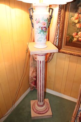 a lamp that is sitting on a pedestal in the corner of a room