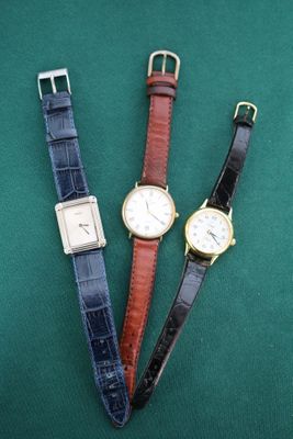 trois montres de couleurs différentes posées sur une surface verte