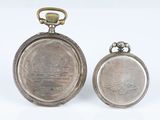 pair of antique pocket watches with silver dials on a white background