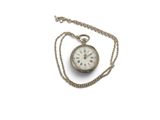 une vieille montre de poche attachée à une chaîne, posée sur une surface blanche