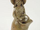 une figurine en céramique représentant une femme portant un chapeau et tenant un panier