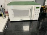 a white microwave with a green cover on top of it
