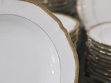 a lot of white and gold plates stacked on top of each other