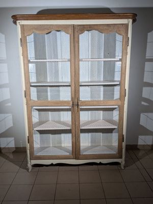 a wooden cabinet with glass doors in the corner of a room