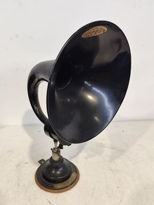 un haut-parleur noir à l'ancienne est posé sur un socle en bois