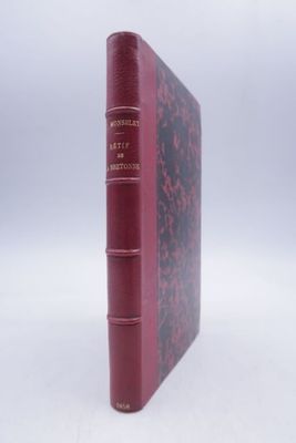 un vieux livre à la couverture rouge posé sur une surface blanche