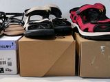 Plusieurs paires de sandales sont posées sur des cartons, sur une table.