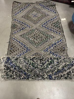 un gros plan sur un tapis posé sur une table, avec une personne debout à côté