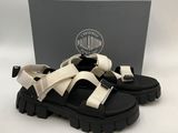 une paire de sandales noires et blanches avec une boîte en arrière-plan