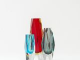 trois vases en verre posés sur une étagère, sur une surface blanche