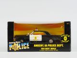 une petite voiture de police dans une boîte, posée sur une surface blanche