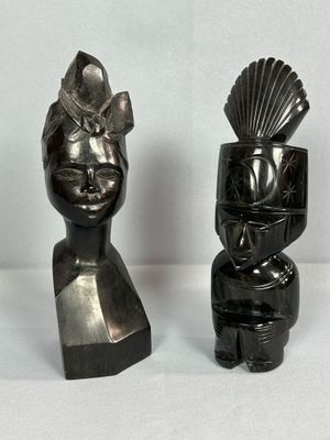 deux sculptures noires représentant un homme et une femme, posées sur une surface blanche