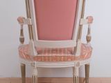 a pink chair sitting on a tile floor next to a white wall