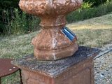 une urne en pierre posée sur un socle à côté d'une chaise