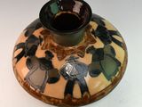 a brown and black vase sitting on a white table