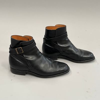 paire de bottines en cuir noir ornées de boucles sur un fond blanc