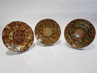 trois assiettes ornées de motifs, posées sur une surface blanche