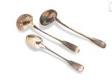 three silver spoons and a spoon rest on a white surface