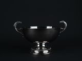 une image représentant une coupe en argent avec une anse en forme de dragon sur fond noir