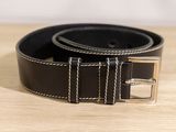 black leather belt with silver buckle on a wooden surface